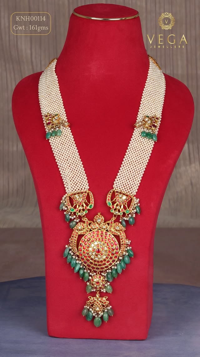 👑 Where Culture Meets LuxuryWhere timeless heritage meets modern luxury. ✨Behold this breathtaking multi-strand pearl haram—a masterpiece designed for the modern bride who carries a royal soul. Weighing 161 grams, this statement piece features a majestic, heritage-inspired circular gold pendant richly studded with vibrant rubies and finished with cascading emerald droplets.A true celebration of South Indian craftsmanship, crafted to turn heads and pass down through generations.✨ Product DetailsProduct Code: KNH00114Gross Weight: 161gmsDesign: Multi-layered pearl strands with heritage ruby-emerald pendant📍 Visit Us / Order OnlineExperience the ultimate bridal jewelry collection at your nearest showroom or contact us directly for personalized shopping.Showrooms: Vijayawada | Hyderabad | Kakinada | Eluru | Guntur🌐 vegajewellers.com📞 +91 99899 43625#VegaJewellers #PearlHaram #SouthIndianJewellery #BridalJewelleryHyderabad #VijayawadaJewellers #TraditionalGoldJewelry #HeritageJewelry #GunturShopping #KakinadaFashion #EluruJewellers #HyderabadBrides #GoldNecklaceDesign by @vegajewellers_jubileehills